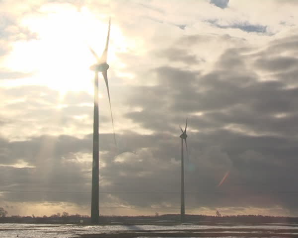 Windmills cloudy sky and sun light is coming through them. Clean ecologic electricity.
