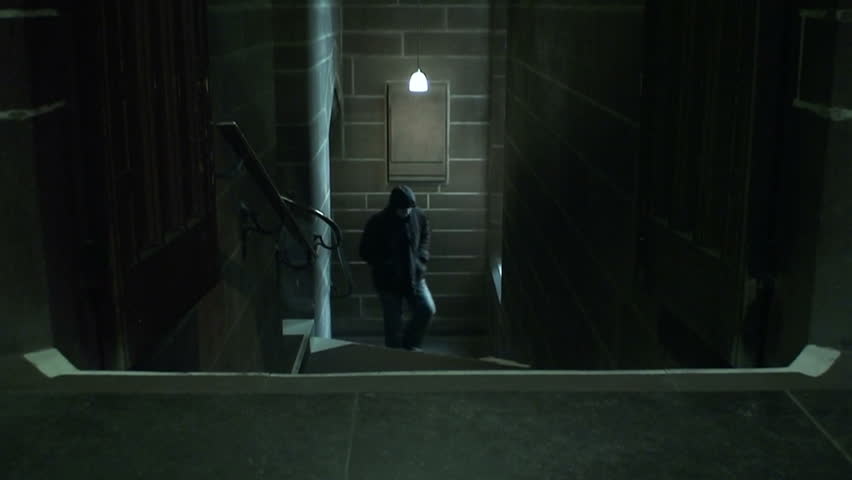 Hooded man fades away whilst walking up stairs in a dark ancient cathedral