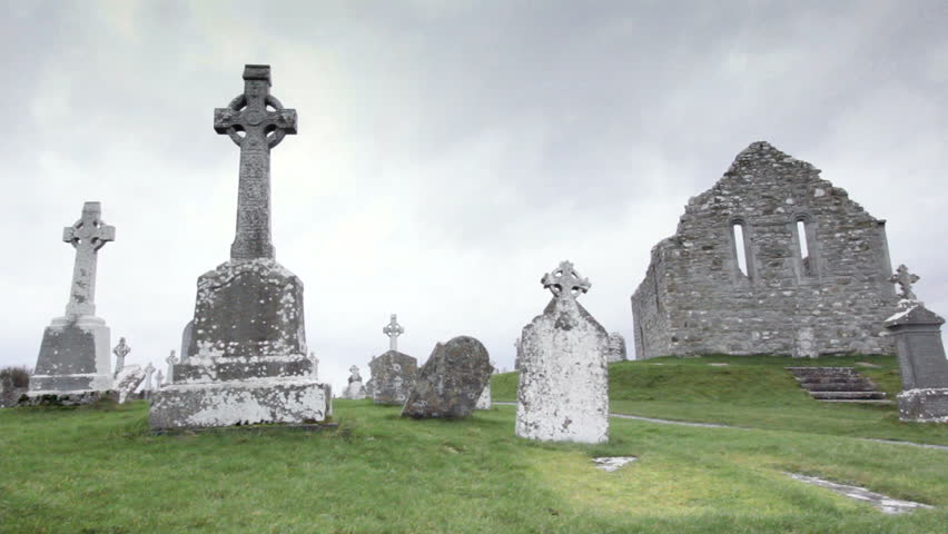 old graveyard with celtic cross graves and ruins of church