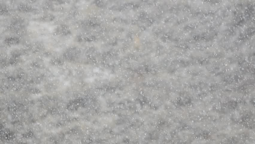 Heavy snow falling through the air with hillside in background