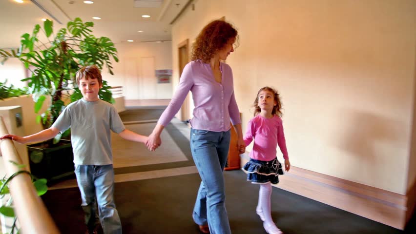 Mother with two kids boy and girl walk along corridor, shown in motion