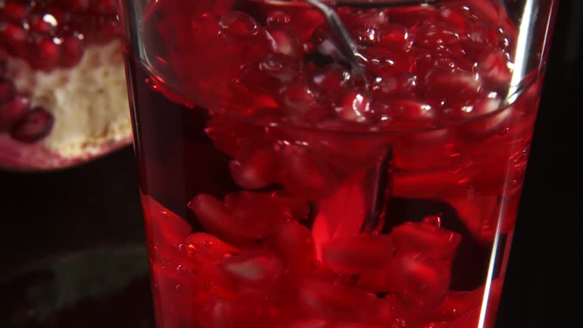 Stirring a drink with pomegranate seeds