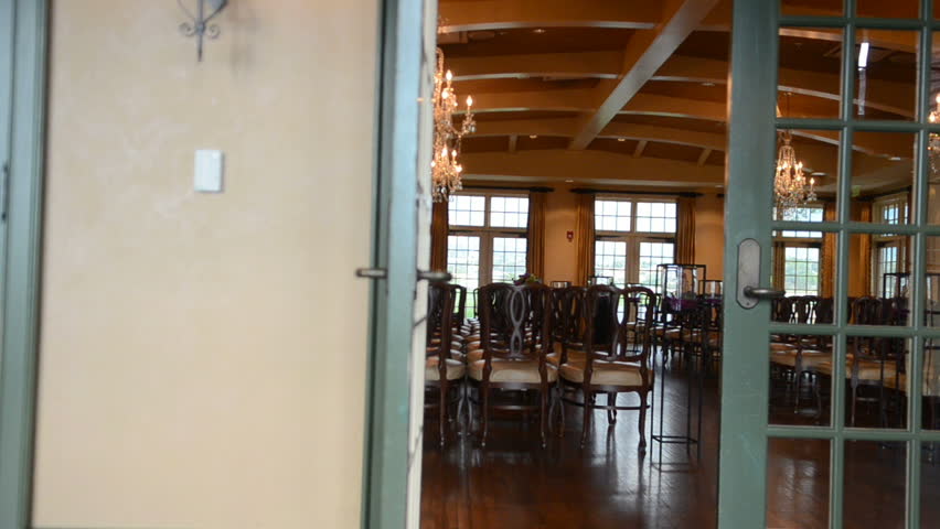 Wedding ceremony setup indoors, panned shot with lady walking through frame getting ready.