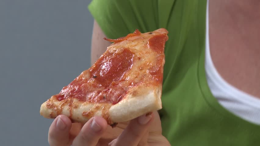 Young woman biting into a slice of pizza