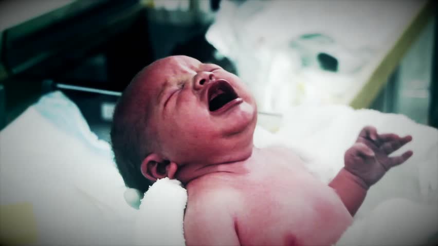 A newborn baby at the hospital being held by the nursing staff.