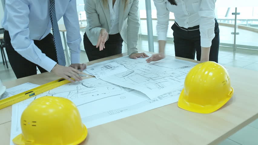Team of architects working together, examining blueprints, choosing, talking, correcting. Camera moving from the bottom upwards