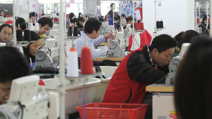 SHENZHEN, CHINA -  JUNE 5: Wide shot of textile factory workers sewing. June 5, 2011 in Shenzhen, China.