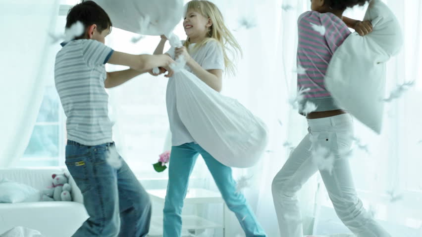 Kids pillow fighting so hard that feathers are falling all around them