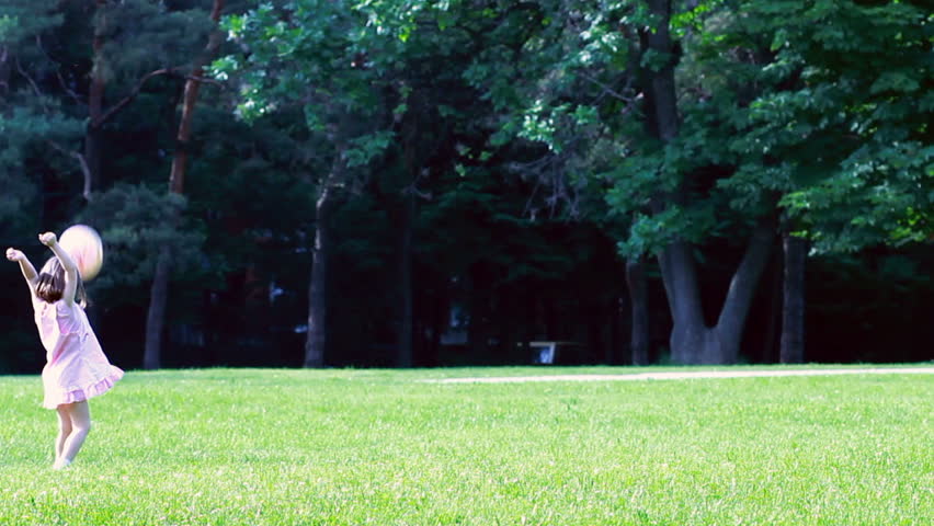 Cute little girl playing on a wide green meadow