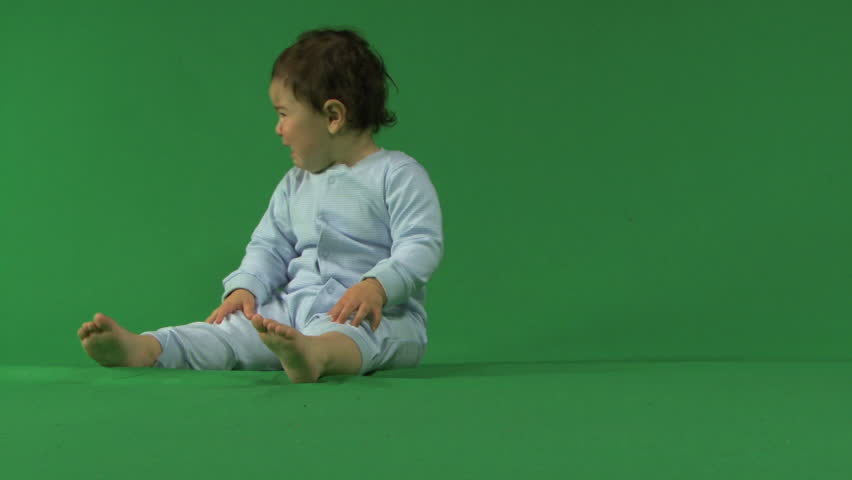 LONG SHOT OF A BABY CRYING ON A GREEN SCREEN