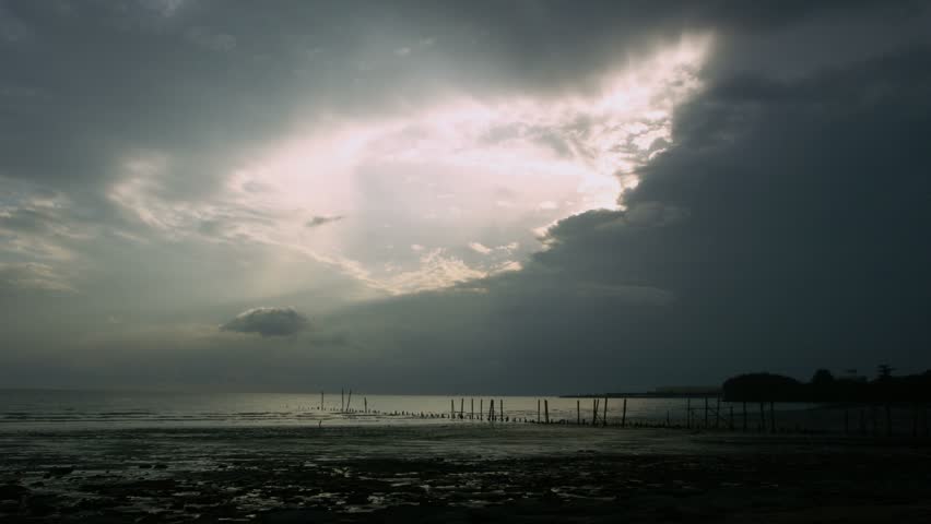 Timelapse of sunset by beach with old pier, Malacca, Malaysia.