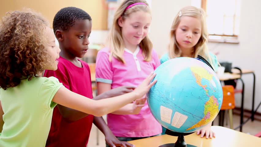 Smiling pupils looking at a globe in the classroom