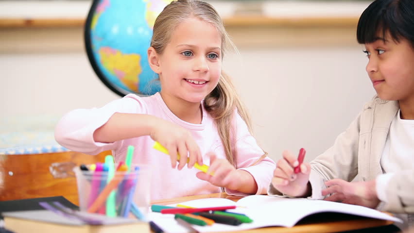 Smiling pupils coloring in the classroom