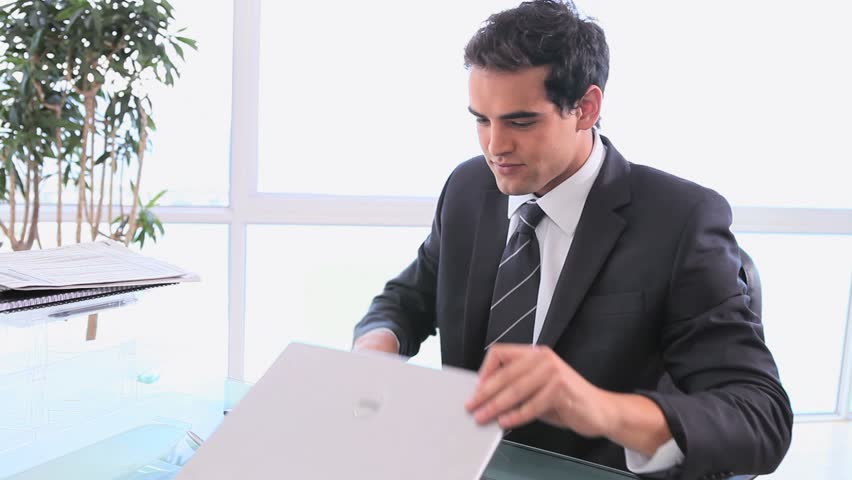 Man turning off his computer to reading the newspaper in his office