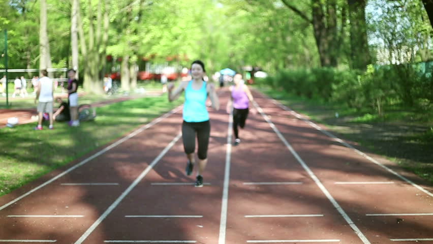 Two young women running on sport track, slow motion
