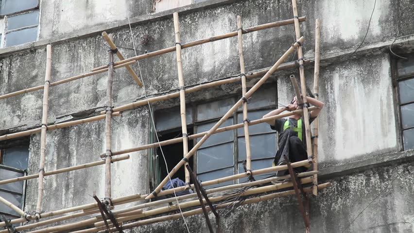 SHENZHEN, CHINA - CIRCA JUNE 2011: worker tying bamboo on an abandoned chinese factory  June 8, 2011 in Shenzhen China.
