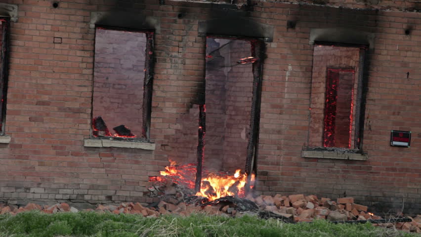 House burning through collapsed door, windows and wall after roof collapse with old adobe bricks walls. Timber and wood structure in blaze of flames. Total destruction. Now insurance is responsible.