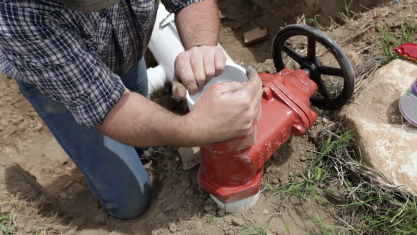 Plumber and farmer fixes and repairs large irrigation water pipe valve in a deep trench fast time lapse. High pressure supply of water to sprinklers to grow crops and agriculture use.