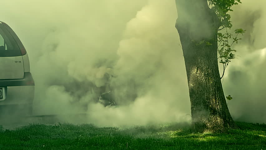 Car engulfed in flames with lot of smoke. A man tries to extinguish the fire with extinguisher 