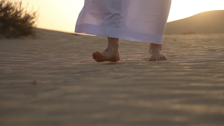Weary man goes in the desert at sunset