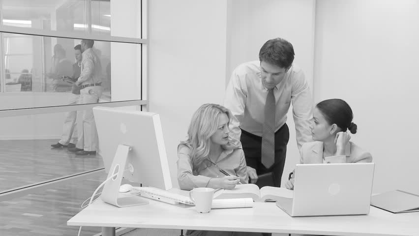 Businesspeople at desk with coworkers in background