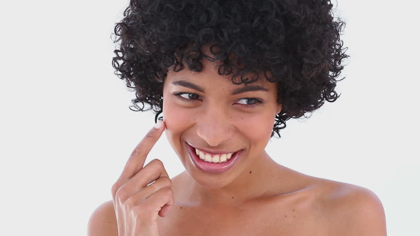 Close-up of a woman applying cream on her face against white background