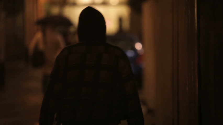 Homeless person walking the streets at night in the rain