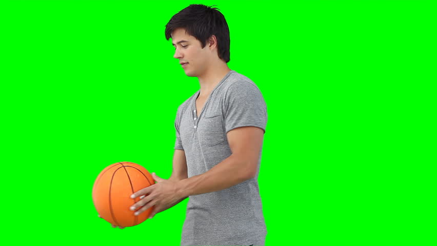 A man spinning a basketball on his hand against a green background