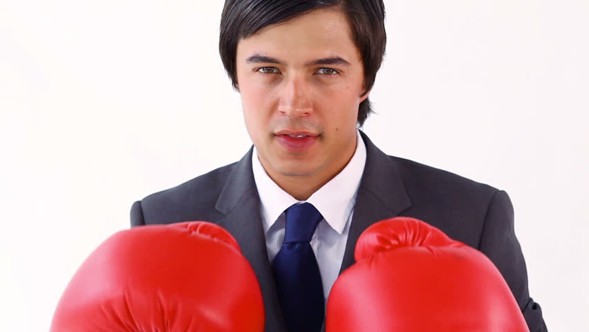 Smiling executive playing with boxing gloves against a white background