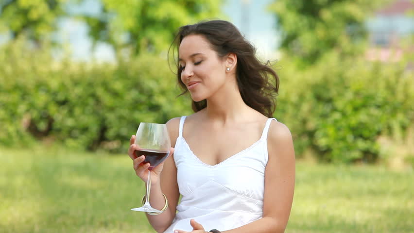 Pretty young woman spending time outdoors, drinking wine and enjoying sunny weather