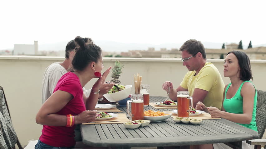 Young happy friends during lunch on terrace
