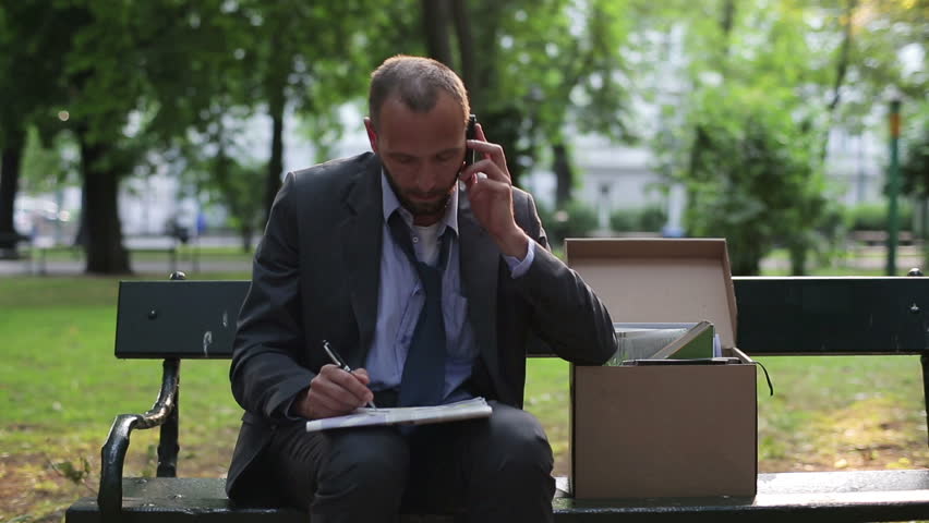 Just fired, unemployed businessman looking for job in newspaper
