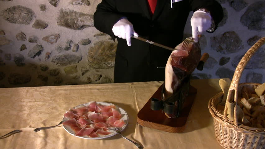 A waiter cut ham in a restaurant.