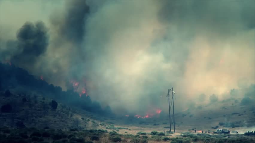 A raging wildfire burns across the mountain leaving a trail of smoke and ash.