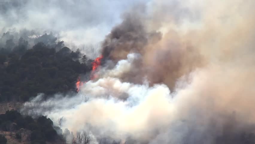 A raging wildfire burns across the mountain leaving a trail of smoke and ash.