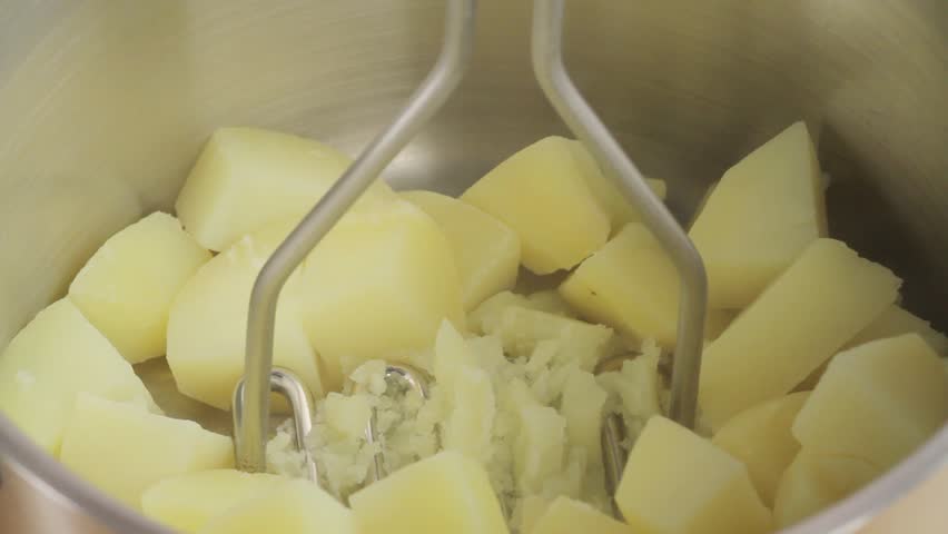Crushing boiled potatoes with a potato masher