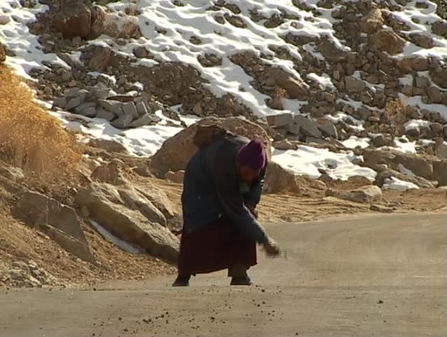 Buddhist pilgrim sweeping the road to the monastery