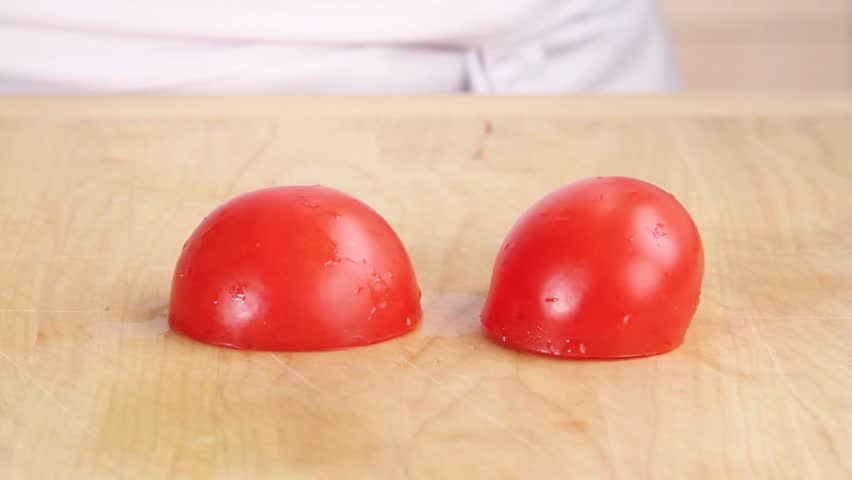 A tomato being cut into wedges