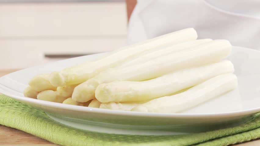 Asparagus with sauce Hollandaise being arranged on a plate