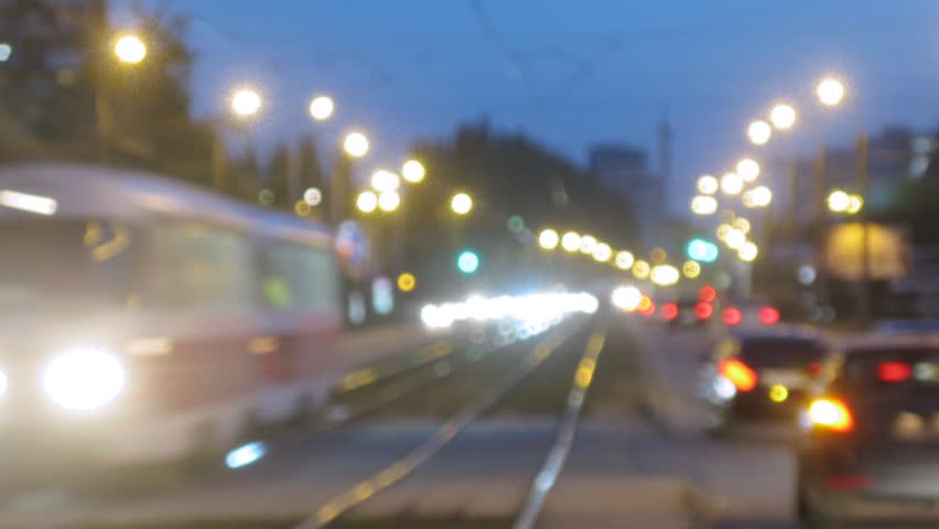 Trams go in middle of highway among stream of cars in evening, time lapse
