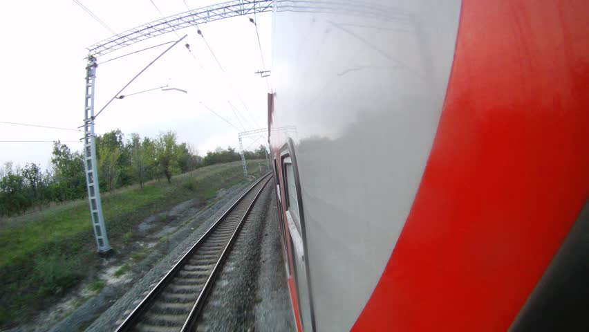 Red train goes along forest belt and rural areas, time lapse