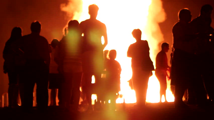 People are standing front of huge fire /  Bonfire of Saint John in Spain