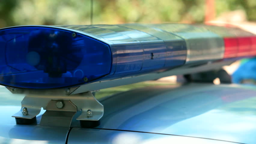 Police car lights flashing, officer leaves the car