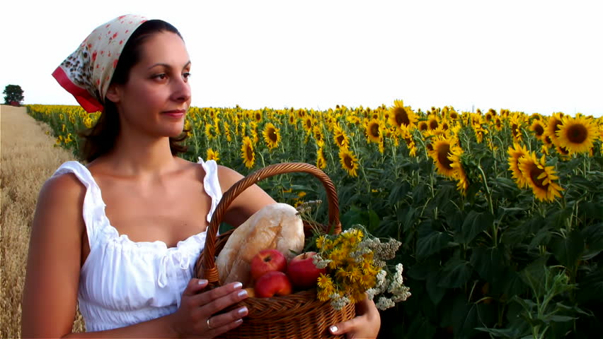 peasant woman eating apple and looking in sunflower field