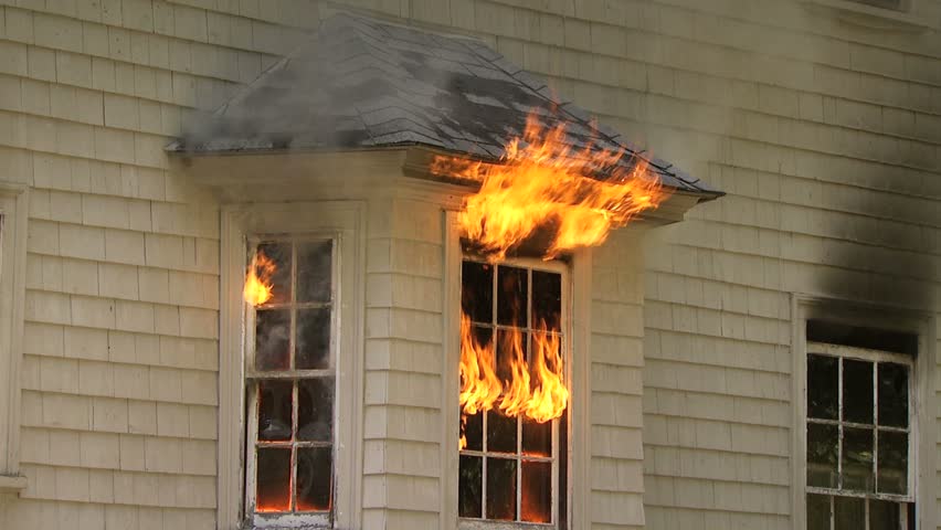 Flames pouring out of window of house on fire - medium shot