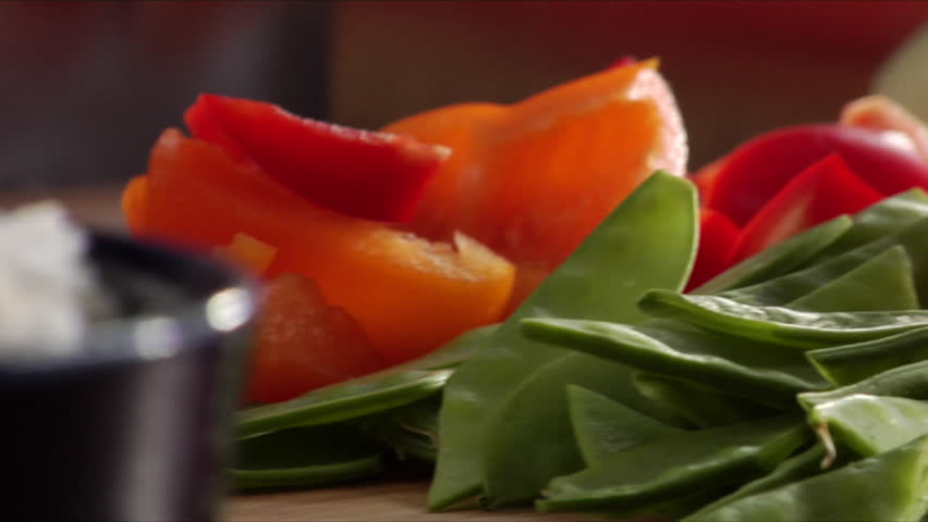 Close-up of Slow Pan of bowl of rice over to chef chopping an onion surrounded by Asian vegetables.