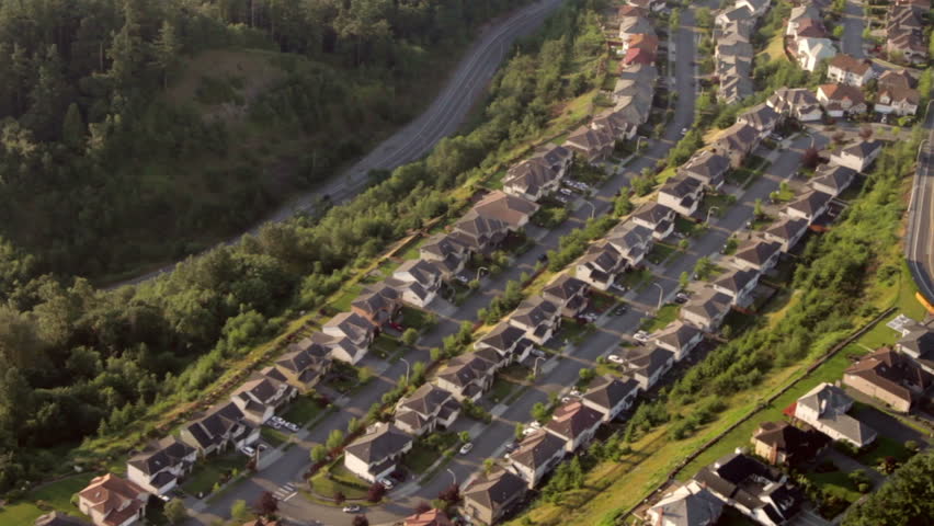 Aerial view from low-flying airplane of roadway around hill and wealthy' suburban neighborhood