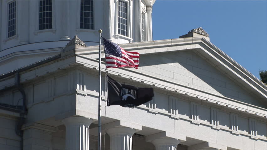 Montpelier, Vermont - CIRCA September 2007: Close up view of flags flapping outside of the State Capitol Building sitting on a green lawn with trees during the day