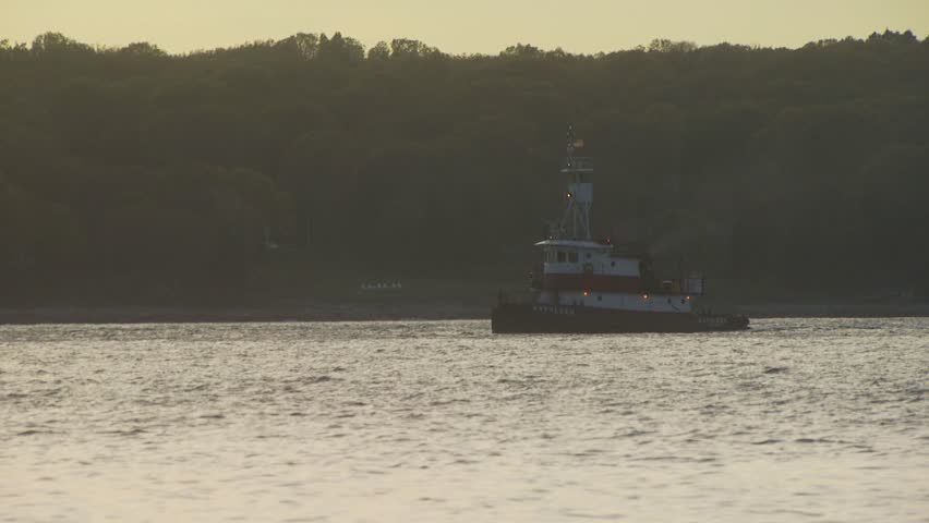 NEWPORT, RHODE ISLAND - AUGUST 3, 2010: Tug boat moving along river at dusk