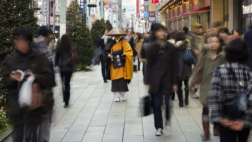 TOKYO, JAPAN - CIRCA MAY 2011: Shinto priest seeking donations (Alms) on the main shopping street in Ginza as various people walk by